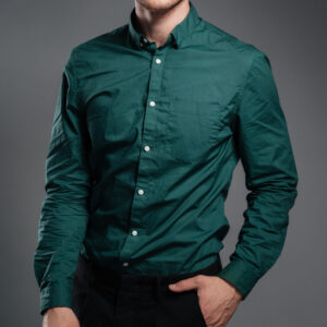 Image of handsome serious man dressed in shirt posing over grey background. Looking at camera.
