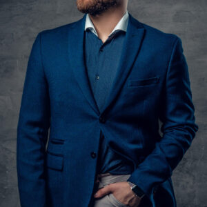 A stylish bearded hipster male dressed in a suit and sunglasses over dark grey background.